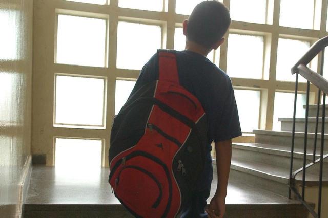 Mochila Pesada Mochila infaltil sendo usada por criança. Mochila com sobrepeso sendo carregada com uma alça apenas.