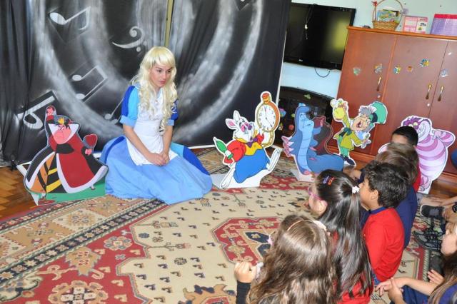 REINVENTAR E EDUCAR MULHER VESTIDA DE ALICE NO PAIS DAS MARAVILHAS CONTANDO A HISTÓRIA PARA UMA RODA DE CRIANÇAS